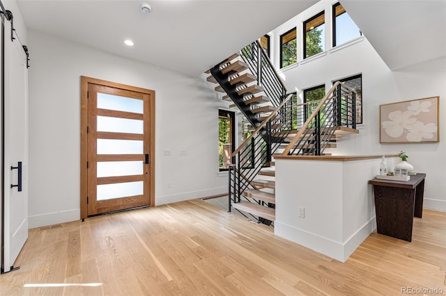 entryway with a barn door and light hardwood / wood-style flooring