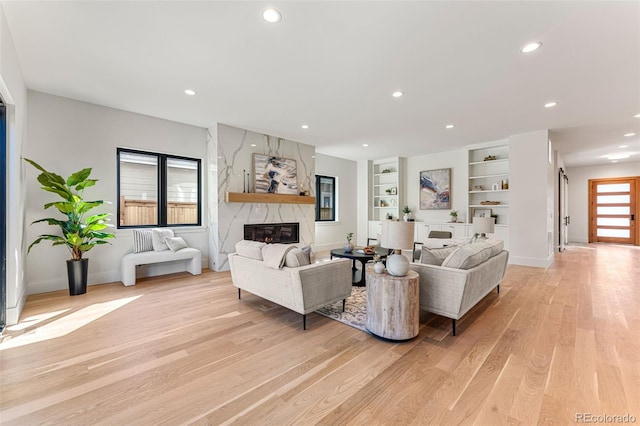 living room with light hardwood / wood-style floors, built in features, and a premium fireplace