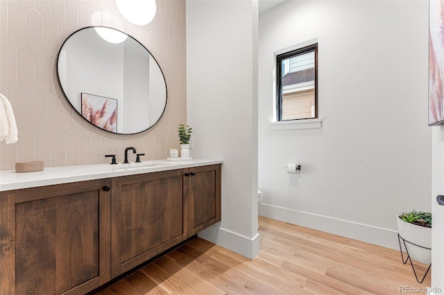 bathroom with wood-type flooring, vanity, backsplash, and toilet