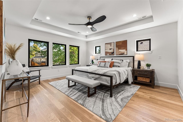 bedroom with a raised ceiling, light hardwood / wood-style floors, and ceiling fan