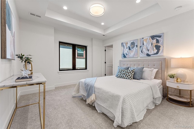 bedroom with light colored carpet and a raised ceiling