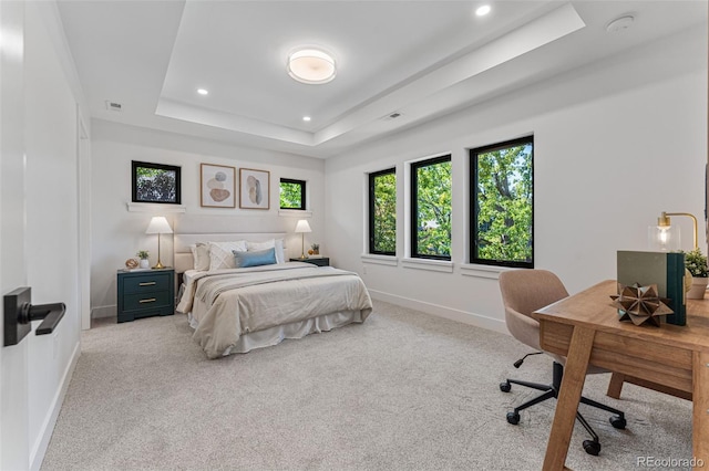 bedroom with a tray ceiling and light colored carpet