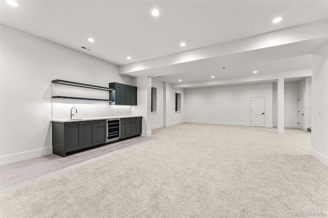 unfurnished living room featuring beverage cooler, sink, and light colored carpet