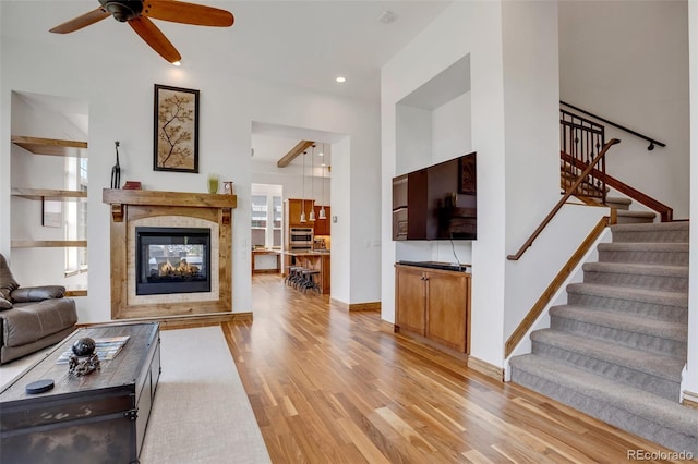 living room with light wood-type flooring, ceiling fan, and a multi sided fireplace