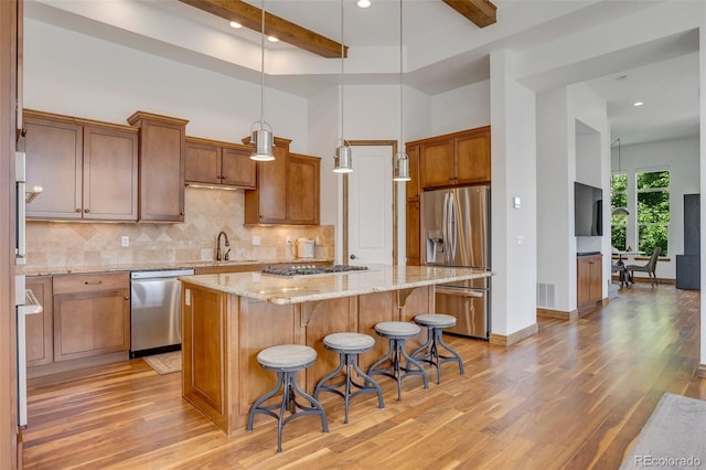 kitchen with a high ceiling, appliances with stainless steel finishes, decorative light fixtures, and a center island