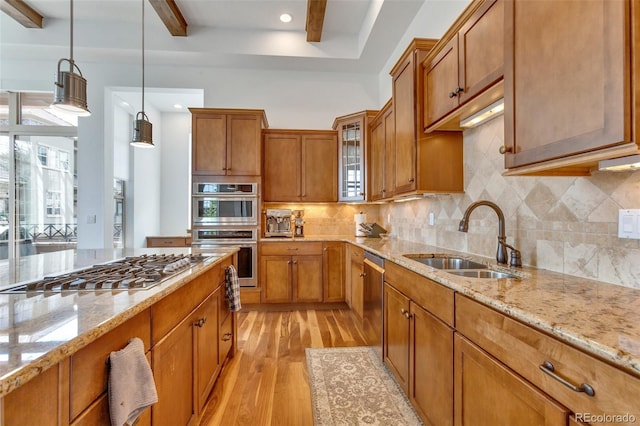 kitchen featuring light stone countertops, hanging light fixtures, stainless steel appliances, light hardwood / wood-style floors, and sink