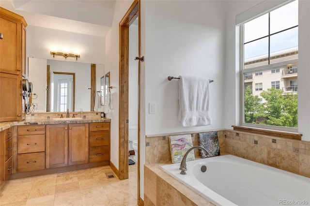 bathroom featuring a relaxing tiled tub, tile patterned floors, vanity, and toilet