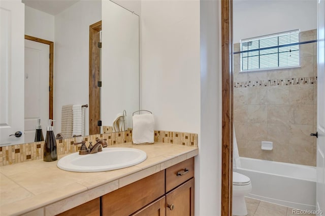 full bathroom featuring toilet, tasteful backsplash, tile patterned floors, tiled shower / bath, and vanity