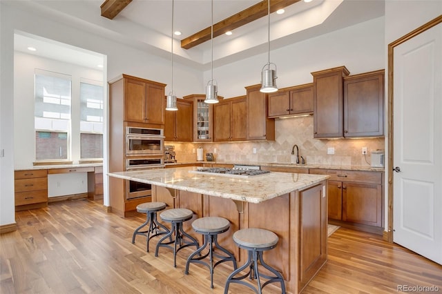 kitchen featuring light hardwood / wood-style flooring, hanging light fixtures, a kitchen island, beam ceiling, and appliances with stainless steel finishes