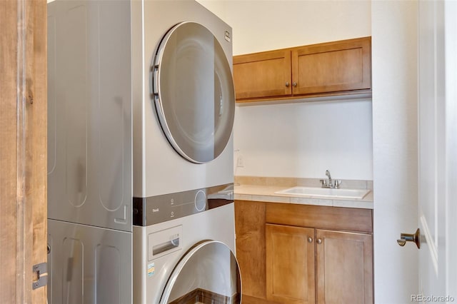 laundry area with sink, cabinets, and stacked washer / drying machine