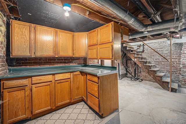 1021 E 23rd Ave, Denver, CO 80205 - kitchen featuring unfinished concrete flooring, brick wall, brown cabinetry, and dark countertops