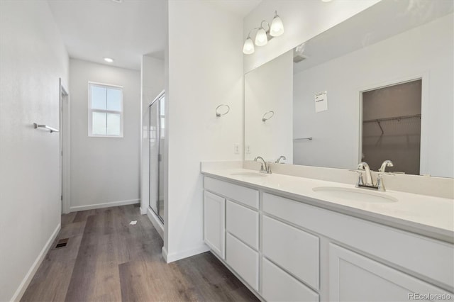 6646 N Nepal St, Aurora, CO 80019 - bathroom featuring wood finished floors, a shower stall, baseboards, and double vanity