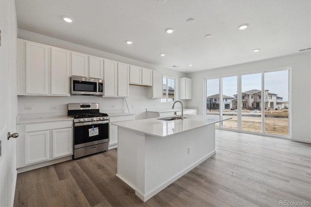 6646 N Nepal St, Aurora, CO 80019 - kitchen with appliances with stainless steel finishes, a sink, wood finished floors, white cabinetry, and recessed lighting