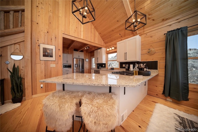 577 Gcr 8952, Granby, CO 80446 - kitchen featuring a chandelier, stainless steel appliances, wooden walls, light wood-style flooring, and white cabinetry