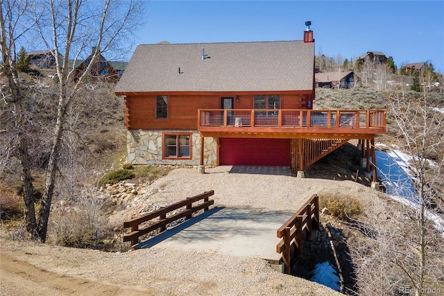 577 Gcr 8952, Granby, CO 80446 - back of house featuring stone siding, driveway, an attached garage, roof with shingles, and a deck