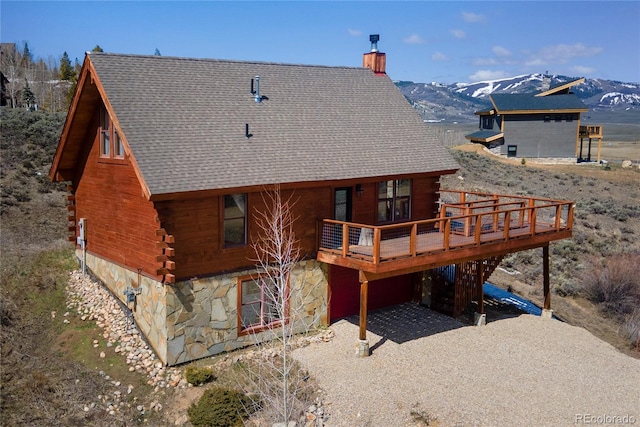 577 Gcr 8952, Granby, CO 80446 - back of property with a chimney, stone siding, log exterior, driveway, and a deck with mountain view