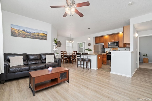 living room featuring light wood-type flooring and ceiling fan with notable chandelier