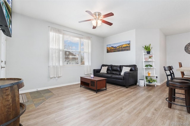 living room featuring baseboards, ceiling fan, and wood finished floors