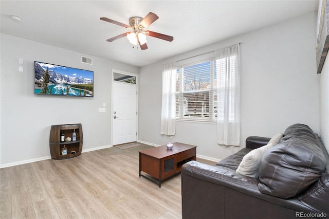 living area featuring visible vents, baseboards, light wood-style floors, and ceiling fan