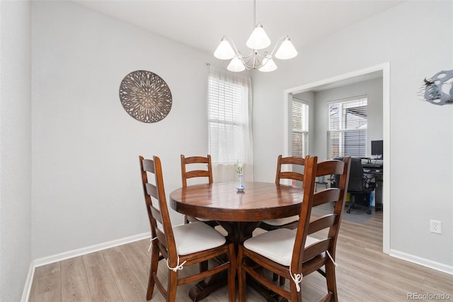 dining room with a notable chandelier, light wood-style floors, and baseboards