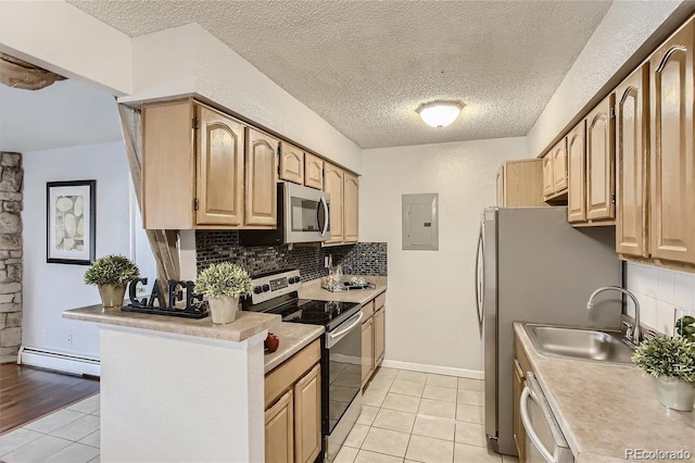 kitchen featuring sink, stainless steel appliances, baseboard heating, tasteful backsplash, and light tile patterned floors