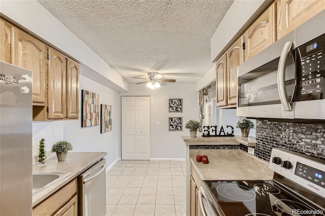 kitchen with appliances with stainless steel finishes, backsplash, light tile patterned floors, and light brown cabinetry