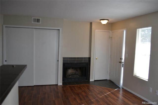 foyer with a tiled fireplace and dark wood-type flooring