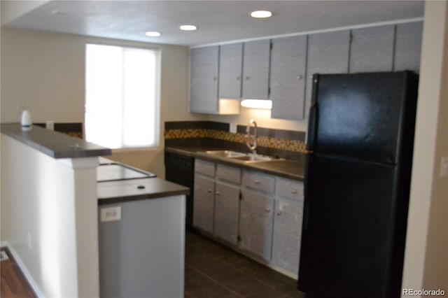 kitchen with plenty of natural light, black refrigerator, cooktop, and sink