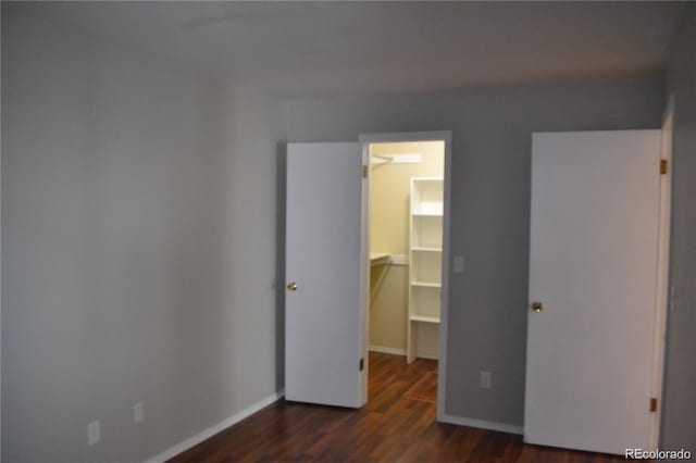 unfurnished bedroom featuring a closet, a spacious closet, and dark hardwood / wood-style flooring