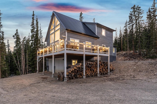 back house at dusk with a garage and a wooden deck