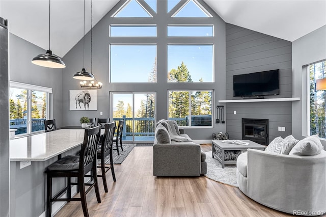 living room featuring a fireplace, high vaulted ceiling, light hardwood / wood-style floors, and plenty of natural light