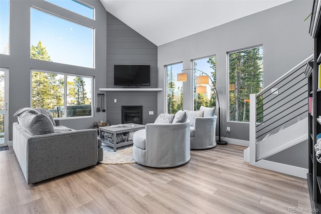 living room with a fireplace, light hardwood / wood-style floors, and high vaulted ceiling