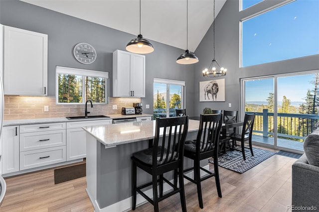 kitchen featuring a kitchen breakfast bar, sink, white cabinets, a center island, and hanging light fixtures