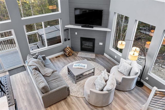 living room with a fireplace, a towering ceiling, and hardwood / wood-style flooring