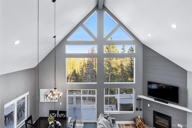 living room featuring a large fireplace, high vaulted ceiling, beamed ceiling, and an inviting chandelier