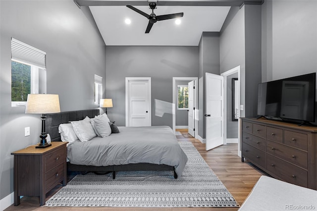 bedroom with ceiling fan, hardwood / wood-style floors, and a high ceiling