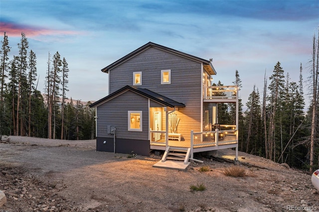 back house at dusk featuring a wooden deck