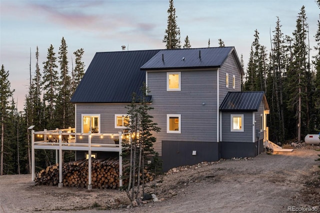 back house at dusk featuring a wooden deck