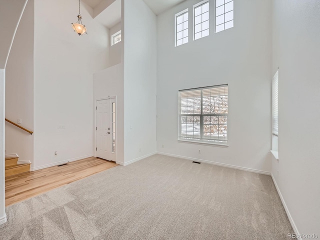 unfurnished living room featuring light wood-type flooring and a high ceiling