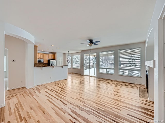 unfurnished living room featuring light wood-type flooring and ceiling fan