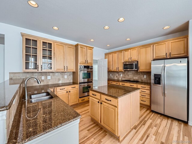 kitchen with stainless steel appliances, sink, light hardwood / wood-style flooring, and a center island