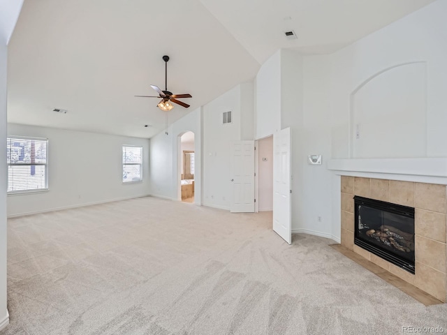 unfurnished living room with high vaulted ceiling, light carpet, ceiling fan, and a fireplace