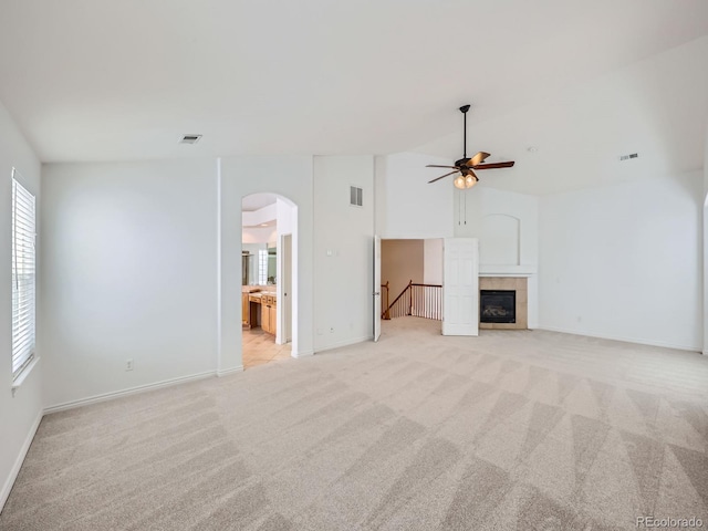 unfurnished living room with a tile fireplace, light colored carpet, and ceiling fan