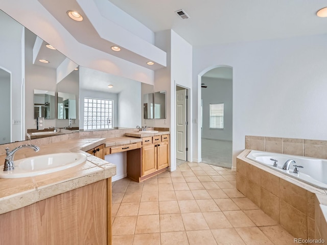 bathroom featuring vanity, tile patterned floors, and a relaxing tiled tub