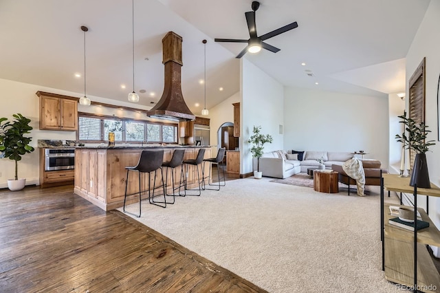 kitchen featuring a center island, open floor plan, a ceiling fan, stainless steel oven, and a breakfast bar area