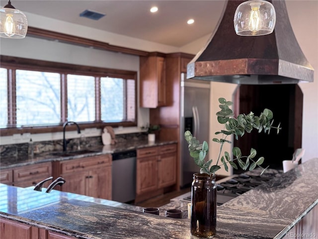 kitchen with recessed lighting, dark stone countertops, custom exhaust hood, appliances with stainless steel finishes, and a sink