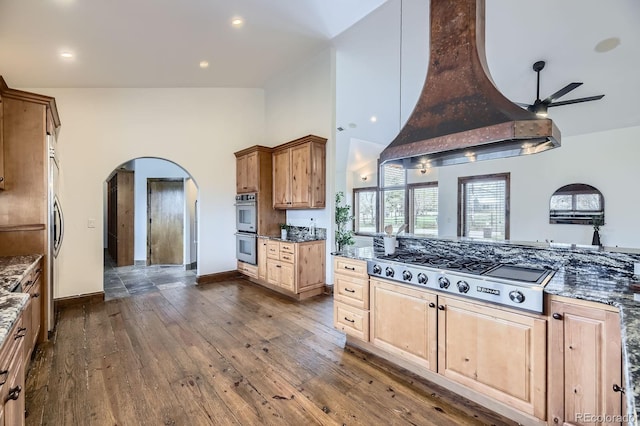 kitchen with high vaulted ceiling, arched walkways, a ceiling fan, custom exhaust hood, and stainless steel appliances