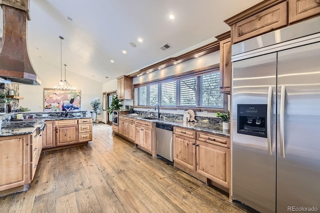 kitchen featuring visible vents, vaulted ceiling, stainless steel appliances, custom range hood, and hardwood / wood-style floors