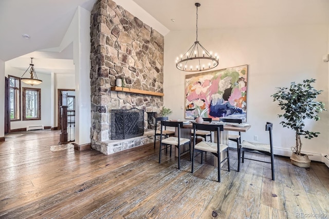 dining room featuring a baseboard heating unit, a fireplace, hardwood / wood-style flooring, and vaulted ceiling