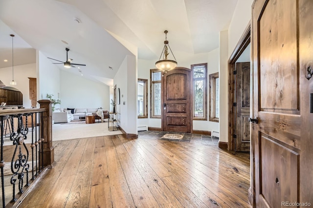 entrance foyer with baseboard heating, hardwood / wood-style floors, a ceiling fan, and vaulted ceiling